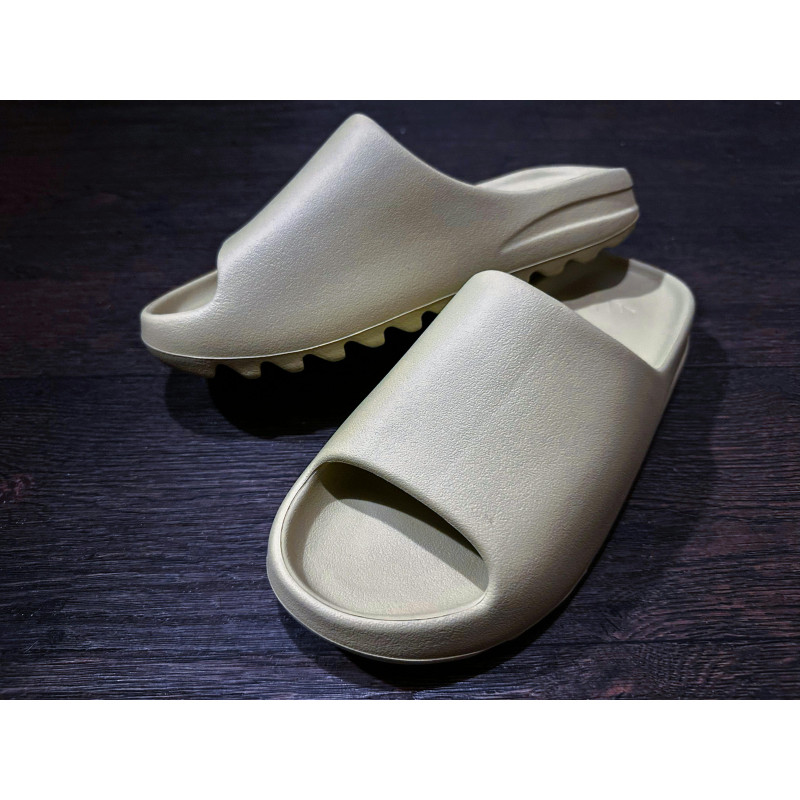Gray Yeezy Slides on a Wooden Surface