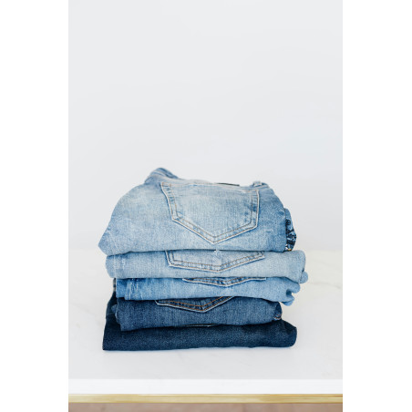 Stack of jeans on white shelf